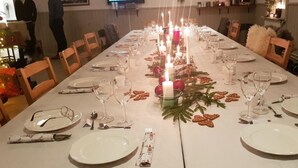 A long dining table set for a meal with candles, plates, glasses, and cutlery.
