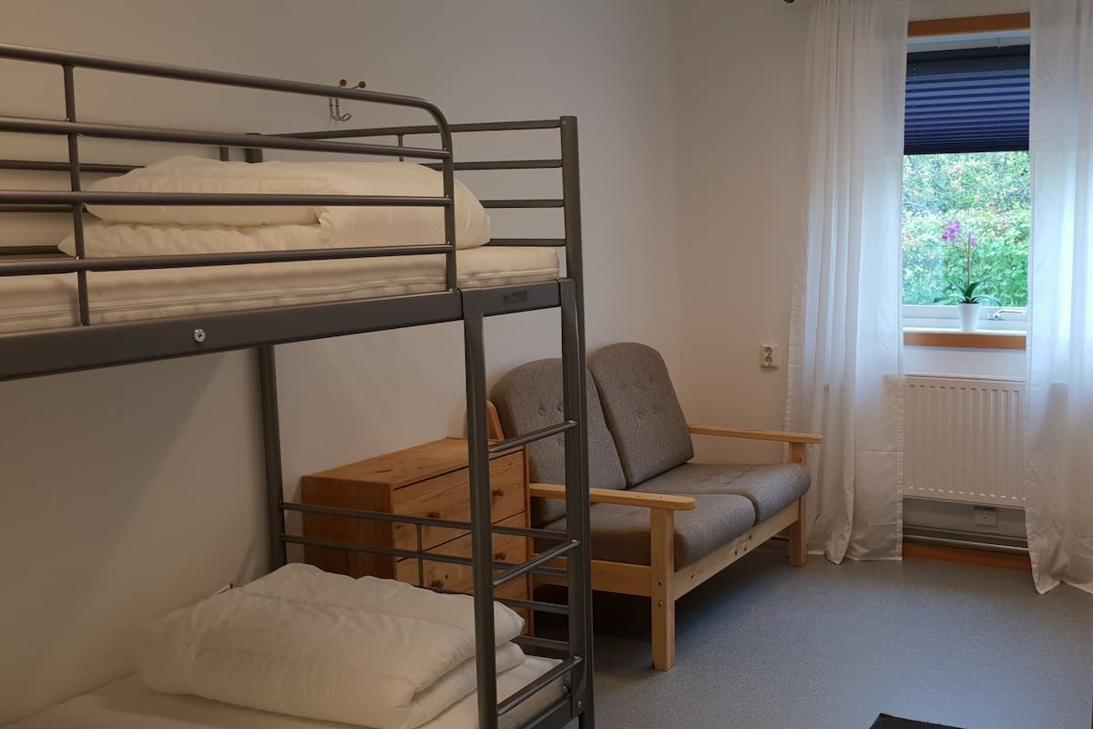 Een slaapzaal met stapelbedden, een eenpersoonsbed, een bureau en een stoel.