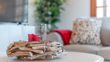 Un vaso di vetro con un fiore rosso appoggiato su un piano di legno su un tavolo bianco.