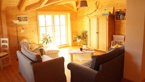 A cozy wooden cabin interior with a sofa, chairs, a table, and a bookshelf. - Fantastic apartment in a log cabin in front of the mountains (Wielenbach)