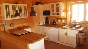 A wooden kitchen with cabinets, a microwave, a sink, and a window. - Fantastic apartment in a log cabin in front of the mountains (Wielenbach)