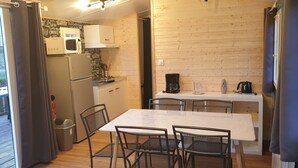 A compact kitchen with a refrigerator, microwave, coffee maker, and a small dining area with a table and chairs.