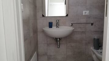 A bathroom with a white sink, a mirror, and a toilet.