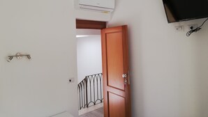 Een kamer met een houten deur, een bevestigde televisie en een airconditioner.