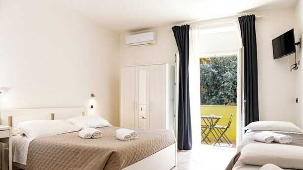 Een hotelkamer met een bed, een bureau en een balkon met een tafel en stoelen.