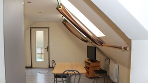 Een kamer met een houten tafel, vier stoelen, een televisie en een radiator.