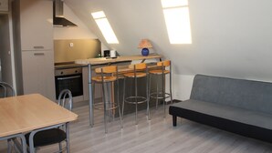 Een kleine keuken met een eethoek, een bank en een bar met krukjes.