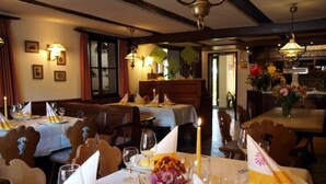 Un restaurante con varias mesas dispuestas para una comida, con manteles blancos, servilletas y velas.