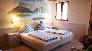 Un dormitorio con dos camas, una mesita de noche, una silla y un cuadro en la pared.