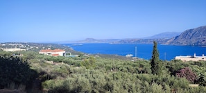 A coastal landscape with a clear view of the sea, a prominent building with a red roof, and surrounding greenery. - The Garden of Zephyrus (Chania)