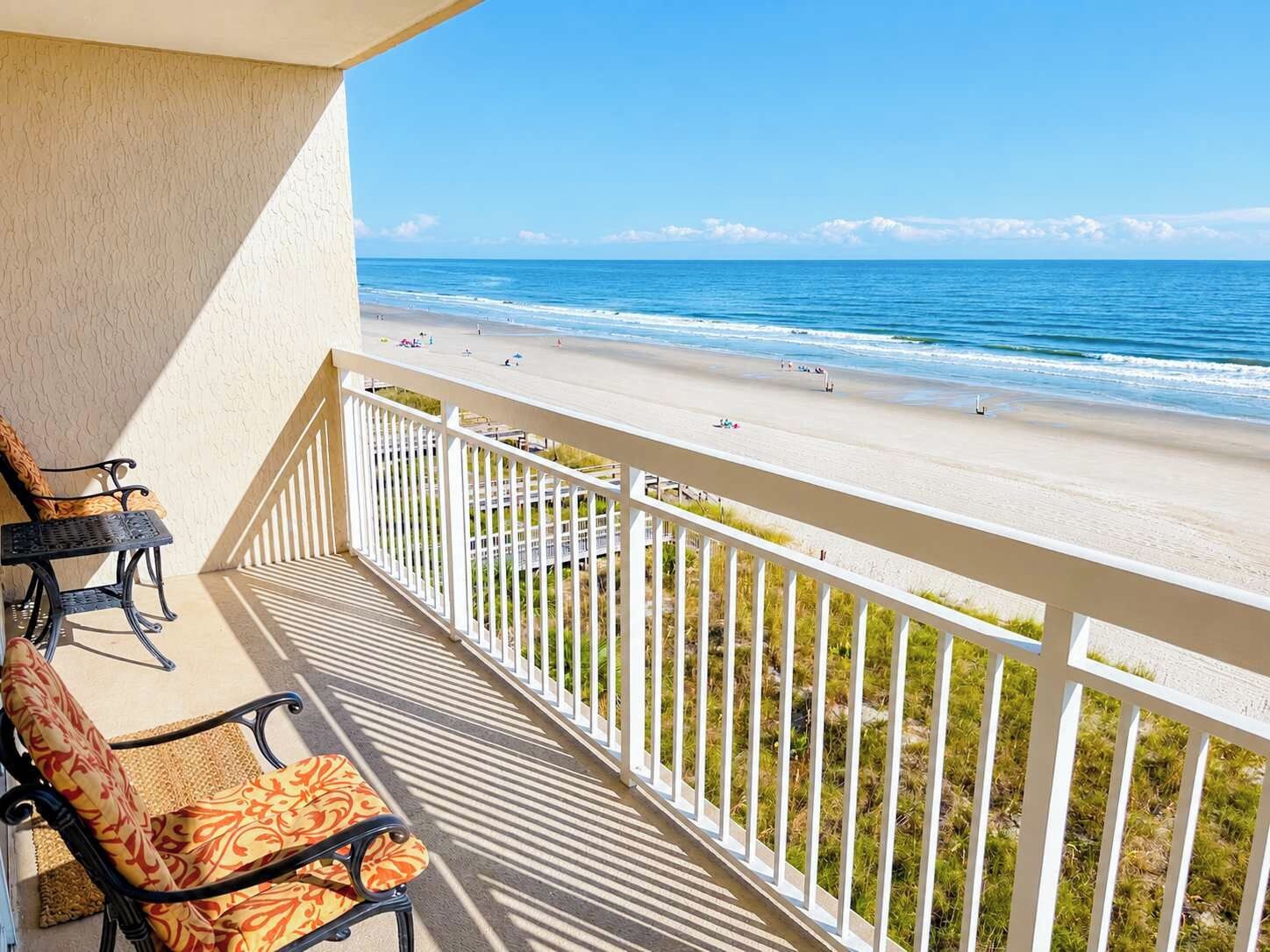 Ein Balkon mit Blick auf einen Strand, ein Stuhl und ein Tisch.