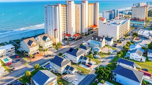 An aerial view of a coastal residential area with beachfront properties, including multi-story buildings and single-family homes. - Crescent Shores S 1309 - Oceanfront Luxury & Unmatched Views! (North Myrtle Beach)