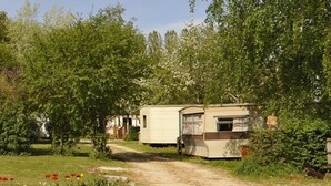 Un camping con varias casas móviles, un sendero de tierra y un parterre de flores.