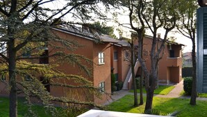 A residential building with a brick facade, a visible staircase, and a well-maintained lawn with trees. -  TWO-ROOM APARTMENT SURROUNDED BY GREEN IN A QUIET RESIDENCE WITH POOL (Sirmione)
