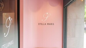 Een receptiegedeelte met een rieten bank, een kleine beeldje van een hond, en een muur met 'STELLA MARIS' aanduiding.