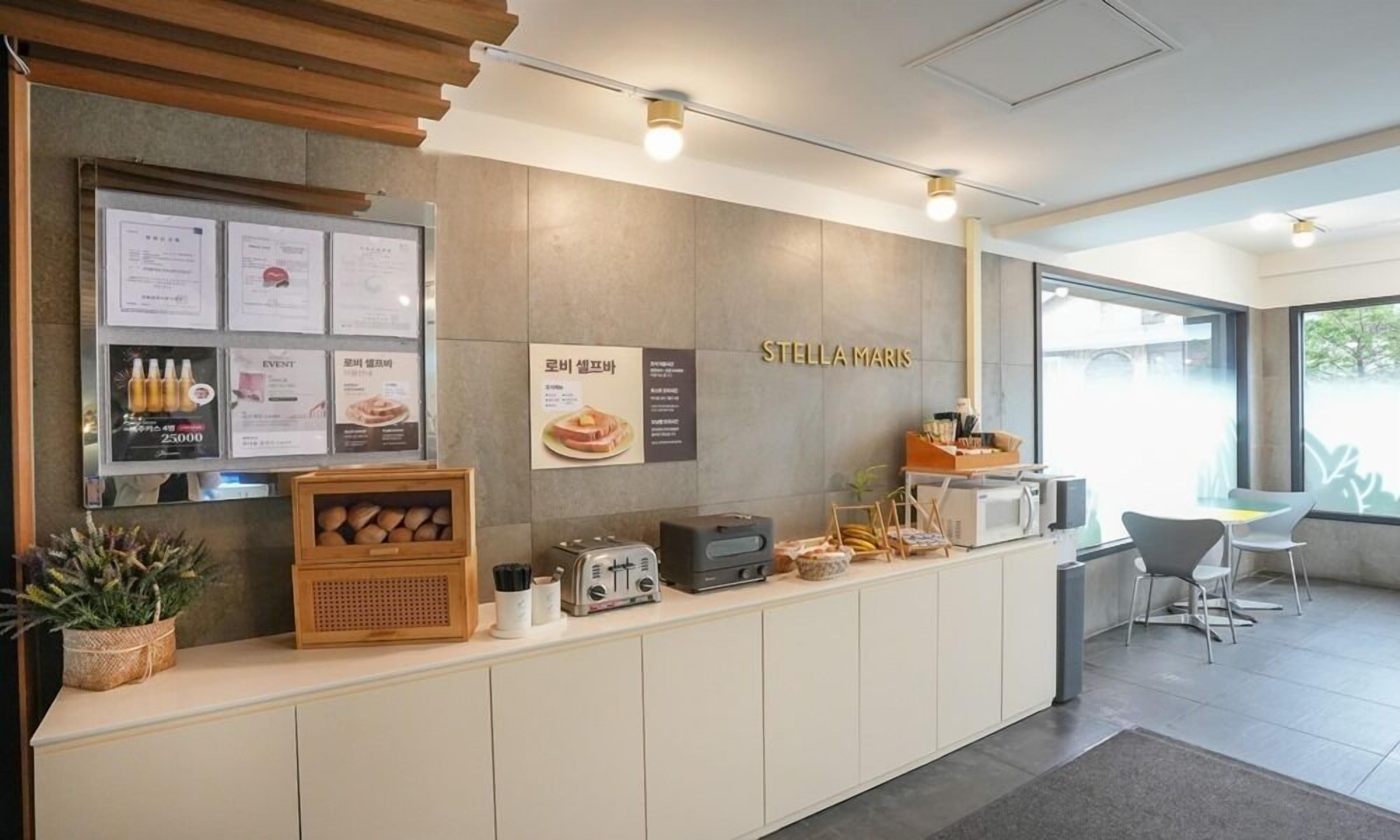 A modern reception area with a wooden counter, a menu board, and a sign for 'STELLA MARIS'.