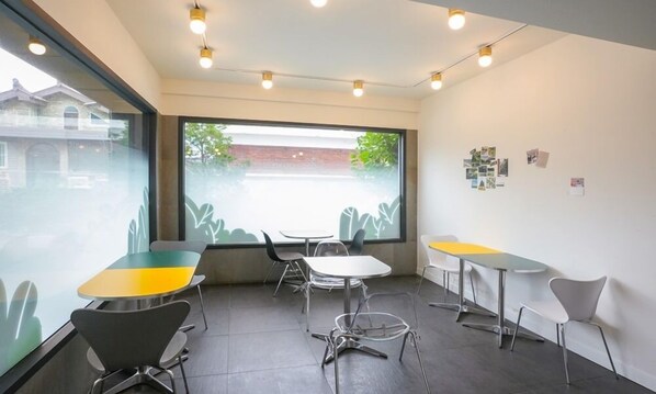 A modern interior with a large window, multiple tables and chairs, and a wall with photos. - Wolmido Stella Maris Hotel (Incheon)
