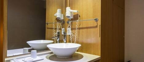 A bathroom with two white sinks, a mirror, and a towel rack.