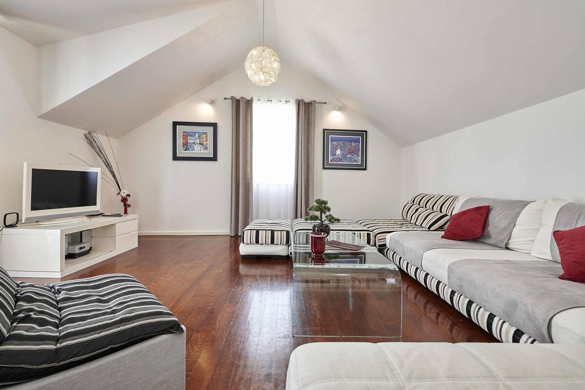 Uma sala de estar moderna com televisão, sofá e mesa de centro.