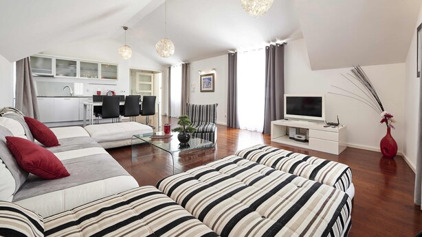A modern living room with a sofa set, a glass coffee table, and a television.