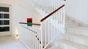 A staircase with white railings and wooden handrails, leading to an upper floor.