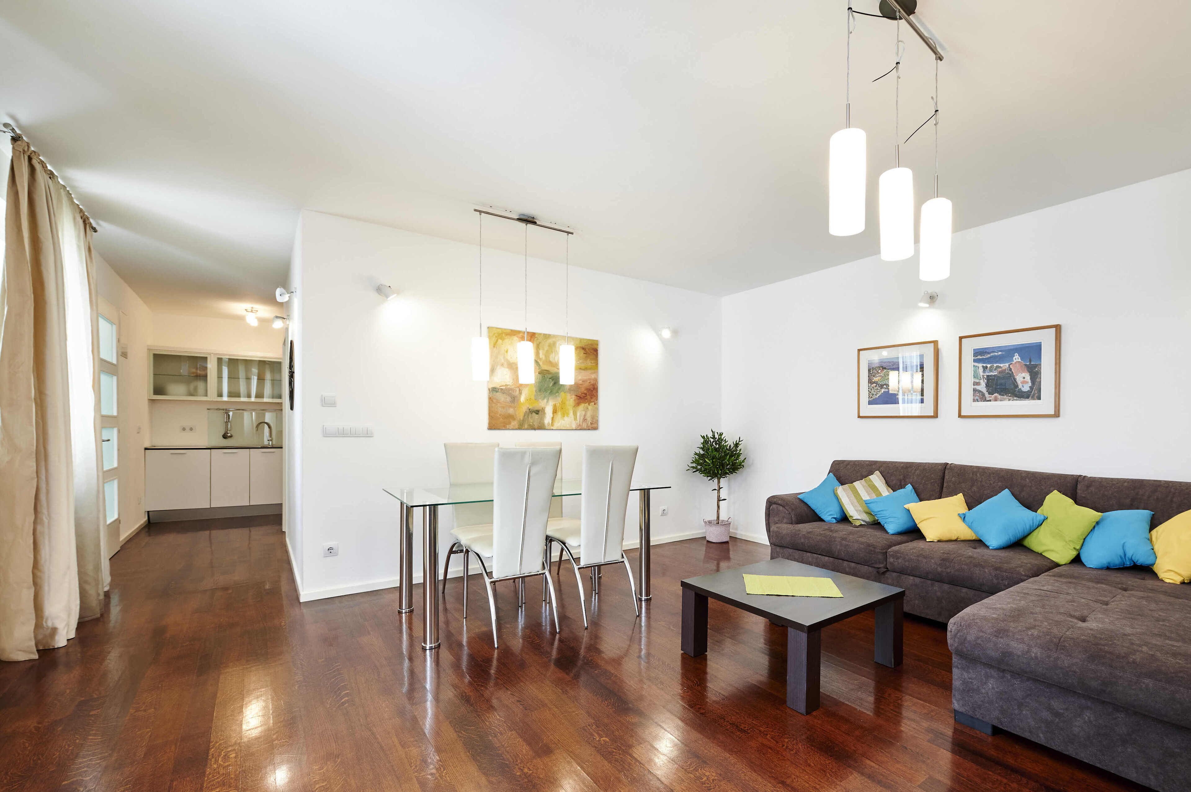 A modern living room with a sofa, coffee table, and dining area with chairs and a table.
