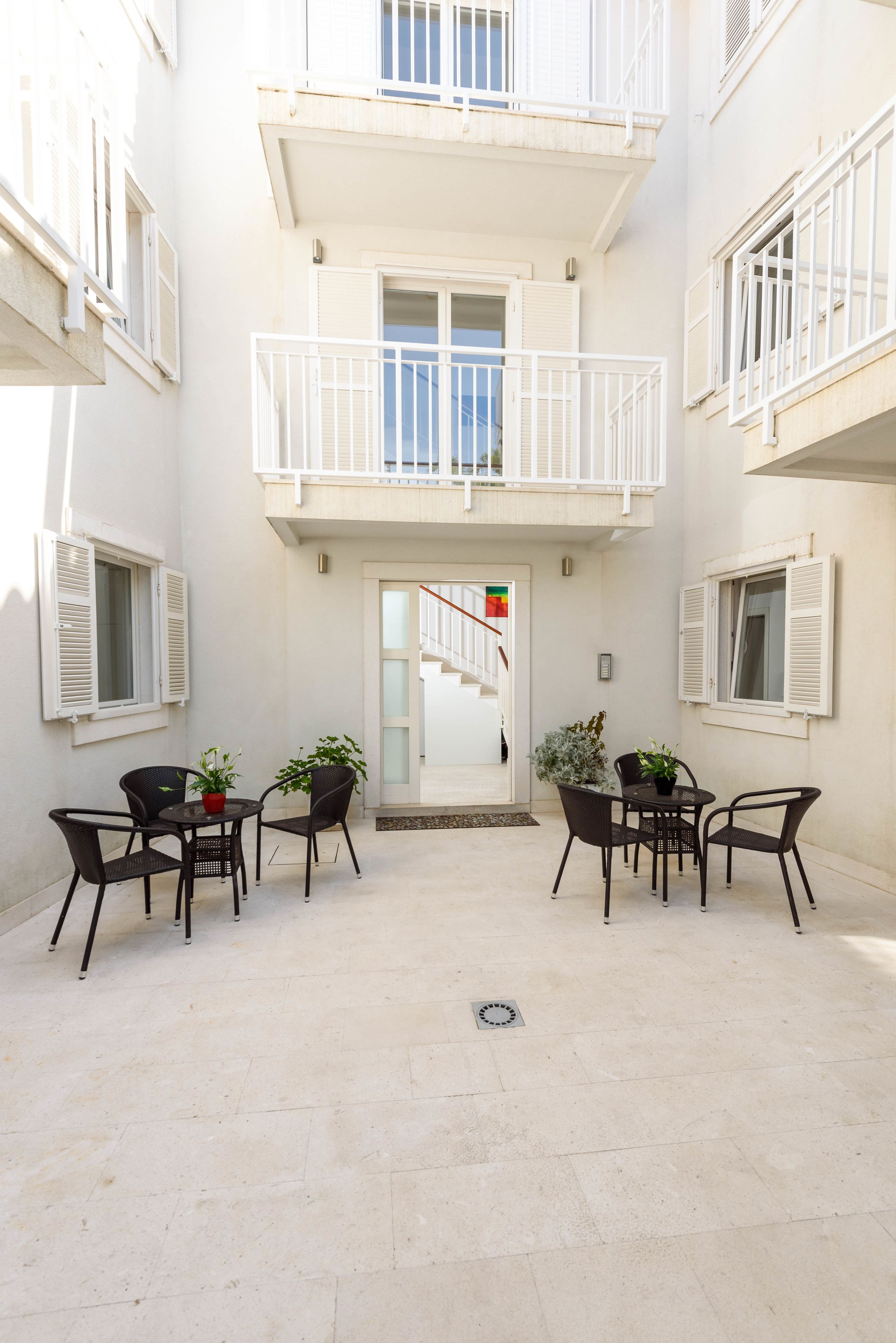 A courtyard with a central seating area, a staircase, and a door with a red flag.