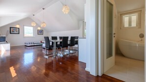 A spacious living area with a dining table and chairs, a television, and a large window.
