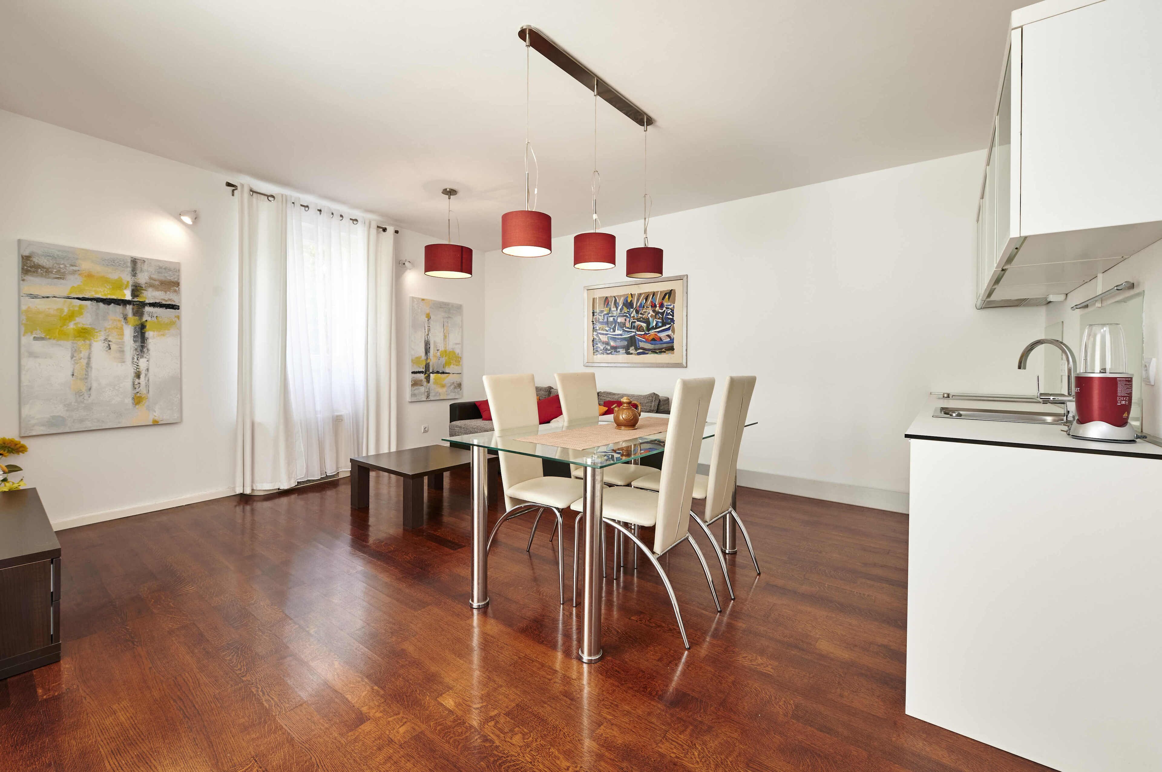 A modern kitchen with white cabinets, a stainless steel sink, and a red kettle.