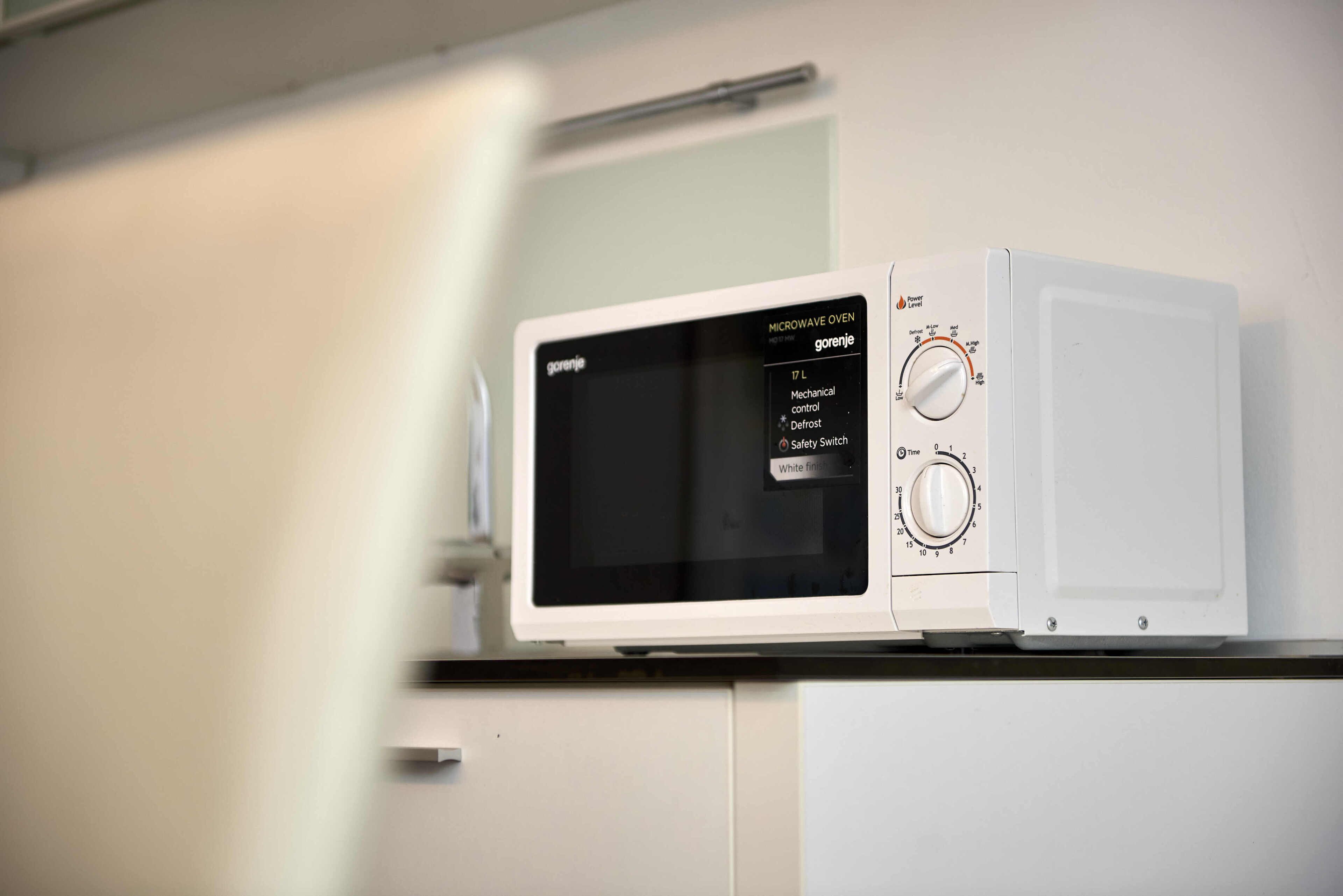 Een witte magnetron met een digitaal display en bedieningsknoppen.
