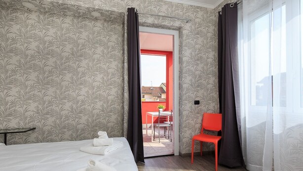 A hotel room with a bed, a table, a chair, and a view of the outside. - Studio with Balcony Rho Fiera R 10 (RHO)