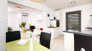 Een moderne keuken met witte kasten, een zwart aanrecht en een raam met jaloezieën.