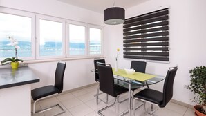 Een moderne eethoek met een glazen tafel, zwarte stoelen, een gele placemat en een potplant.