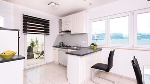 Een moderne keuken met witte kasten, een zwart aanrecht en uitzicht op zee.
