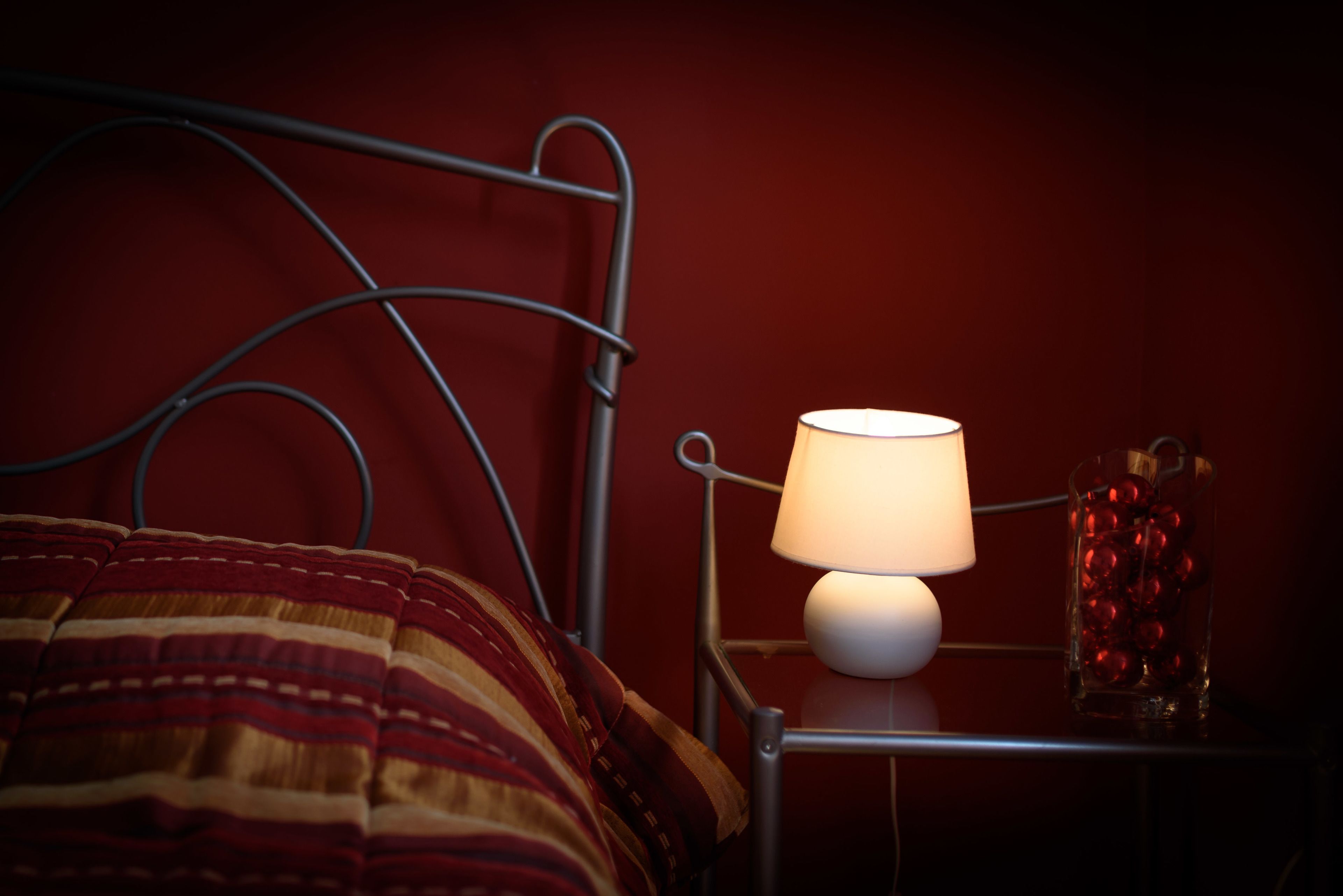 Un lit avec un cadre en métal et une lampe sur une table de chevet.