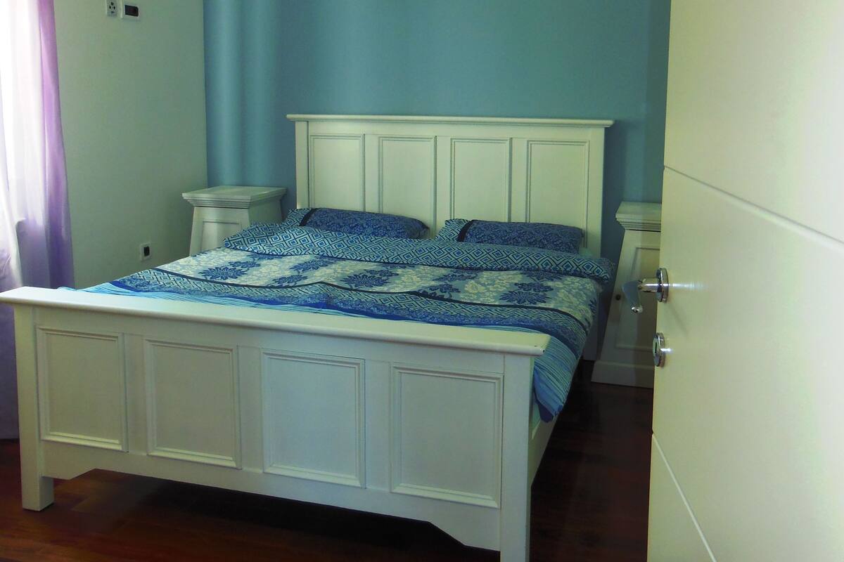 A bedroom with a bed, a ceiling fan, and a white door.