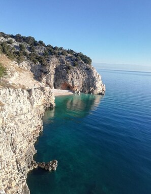 A coastal landscape with rocky cliffs and clear blue sea.