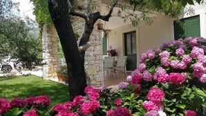 A stone house with a garden, a dining area, and a visible door. - Villa Brumnic Apartments (Moscenicka Draga)