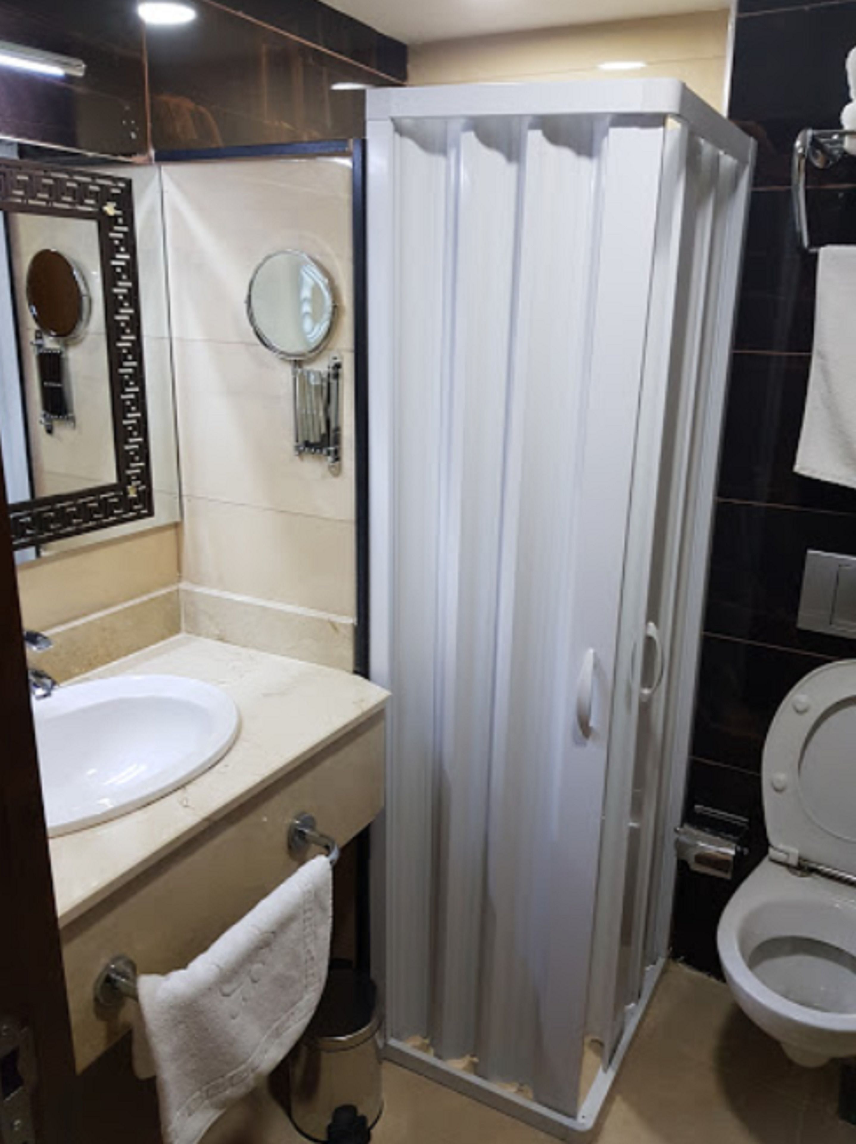 Un baño con cabina de ducha, lavabo, espejo e inodoro.