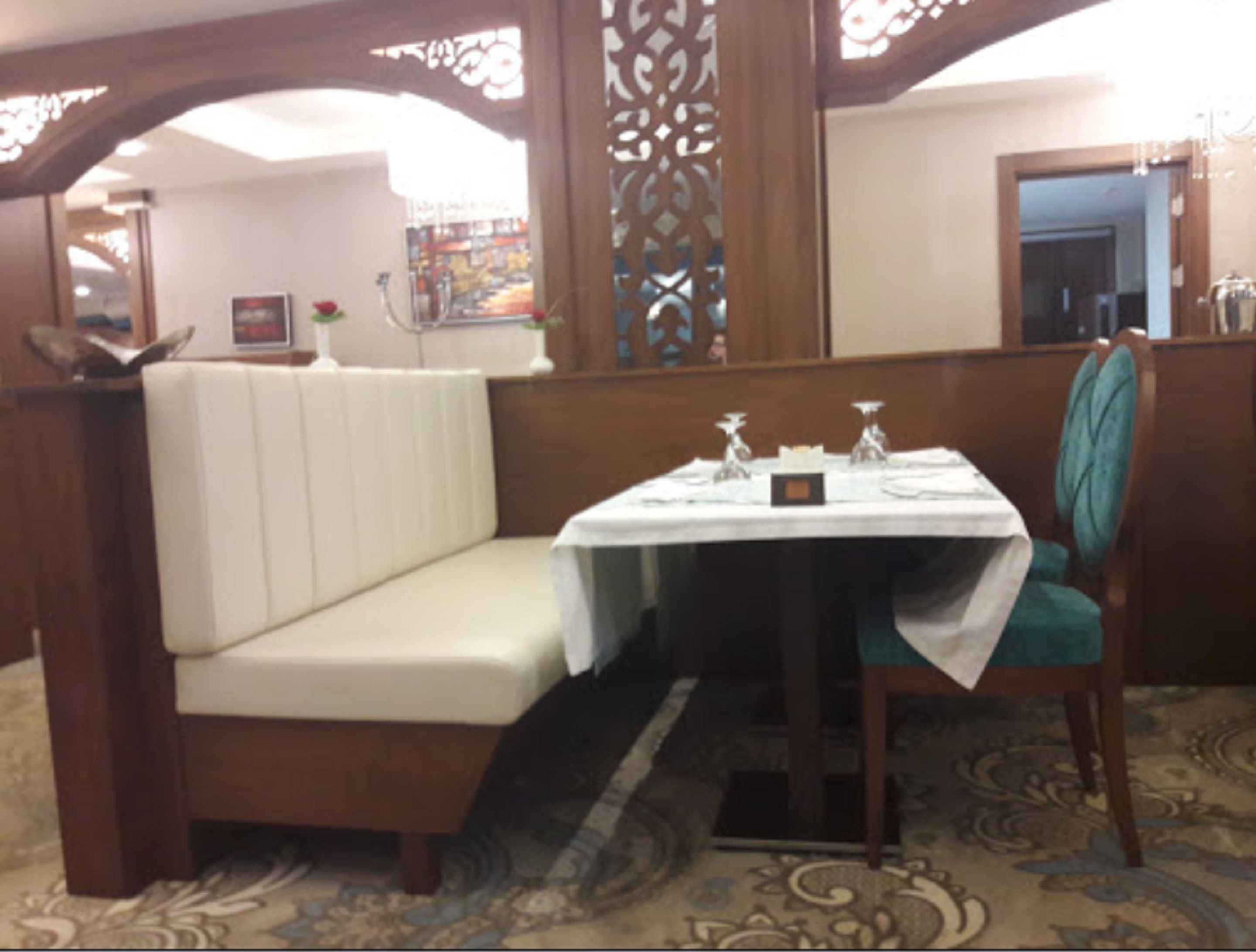 Un comedor con asientos tipo cabina, una mesa dispuesta con cubiertos y un separador decorativo.