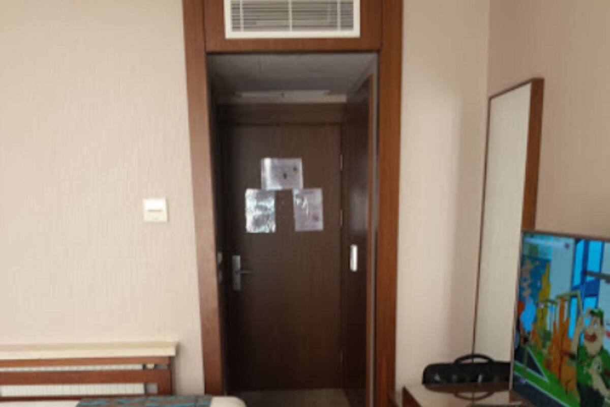 Hotellihuone, jossa on kaksi sänkyä, työpöytä, tuoli ja taulu seinällä.