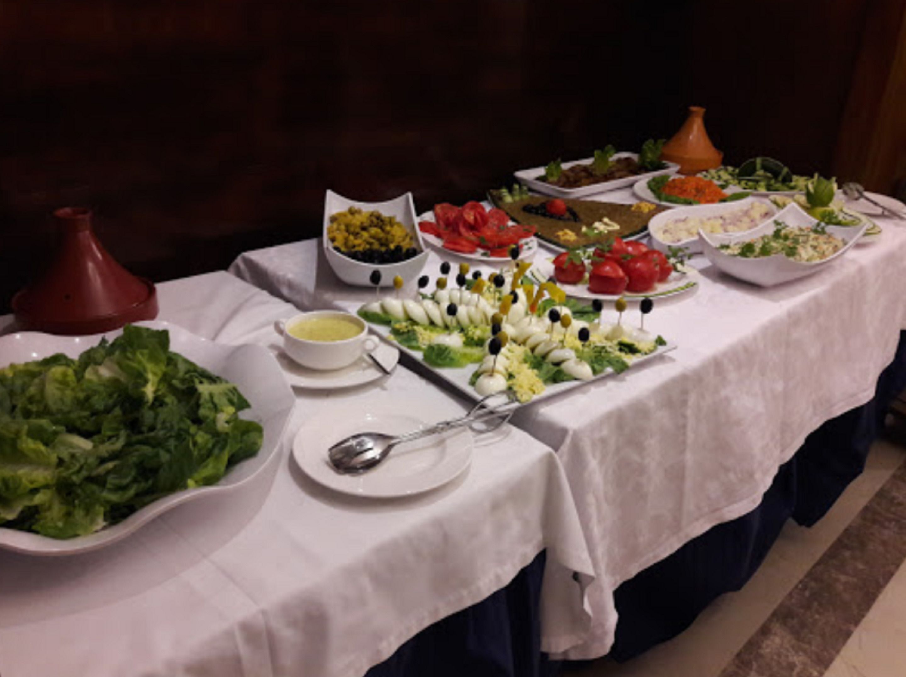 A buffet table with various dishes, including salads, vegetables, and dips.
