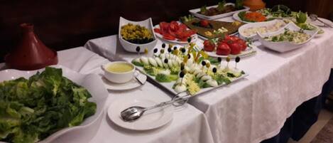 A buffet table with various dishes, including salads, vegetables, and dips.