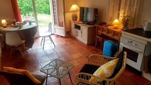 A cozy living room with a television, a dining table, and a kitchen area. - Riad des Vignes (Ramatuelle)