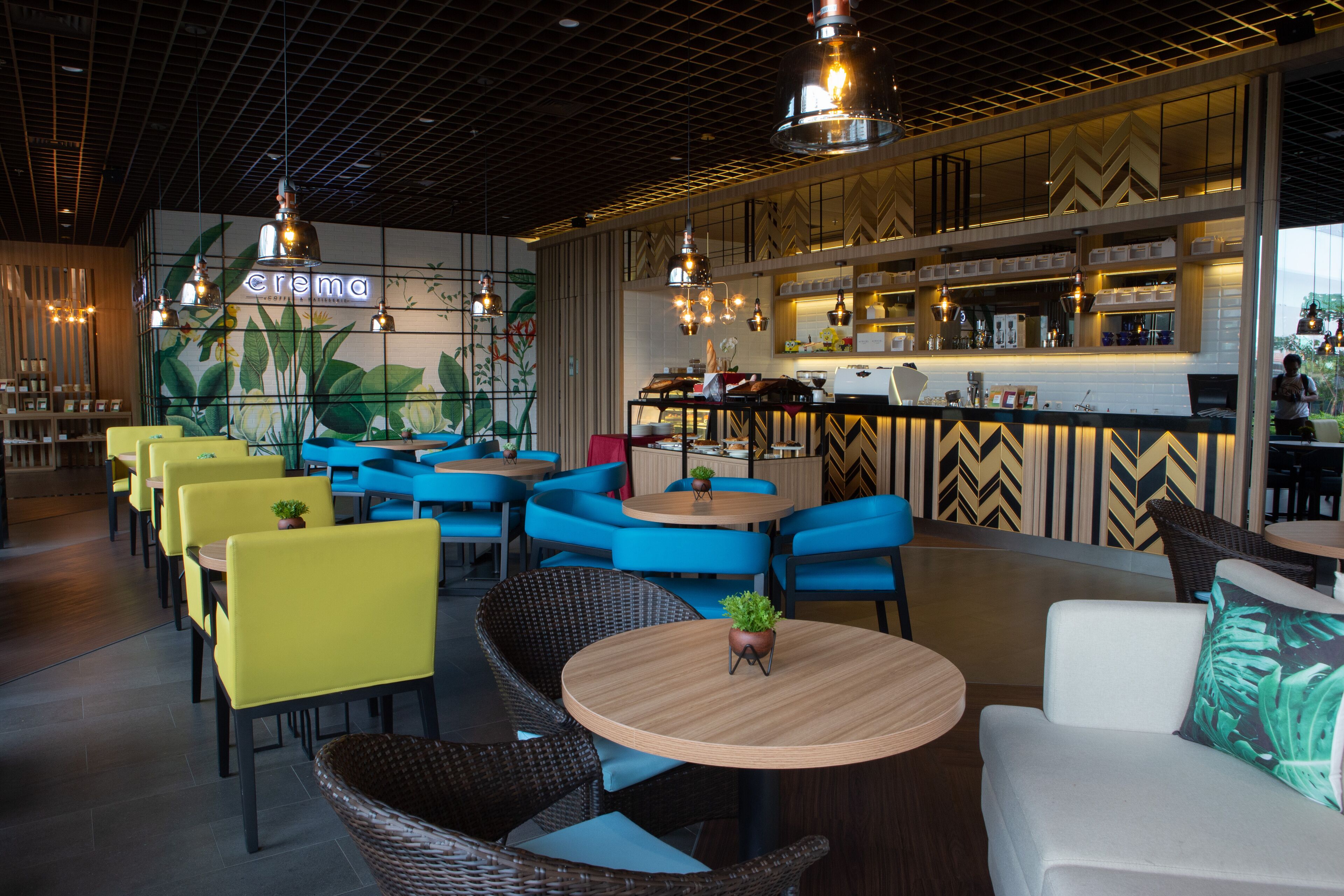 Een restaurant met gele en blauwe stoelen, een bar en een plafond met een rasterpatroon.