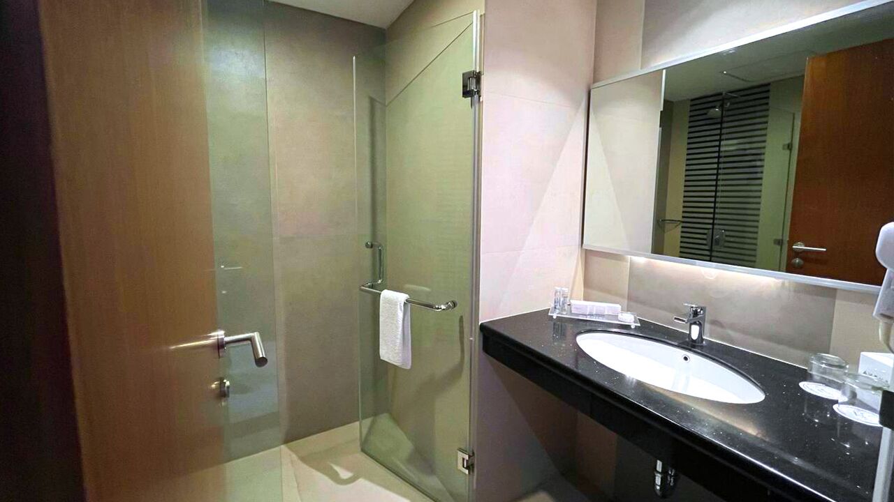 A modern bathroom with a glass-enclosed shower, a black countertop sink, and a large mirror.