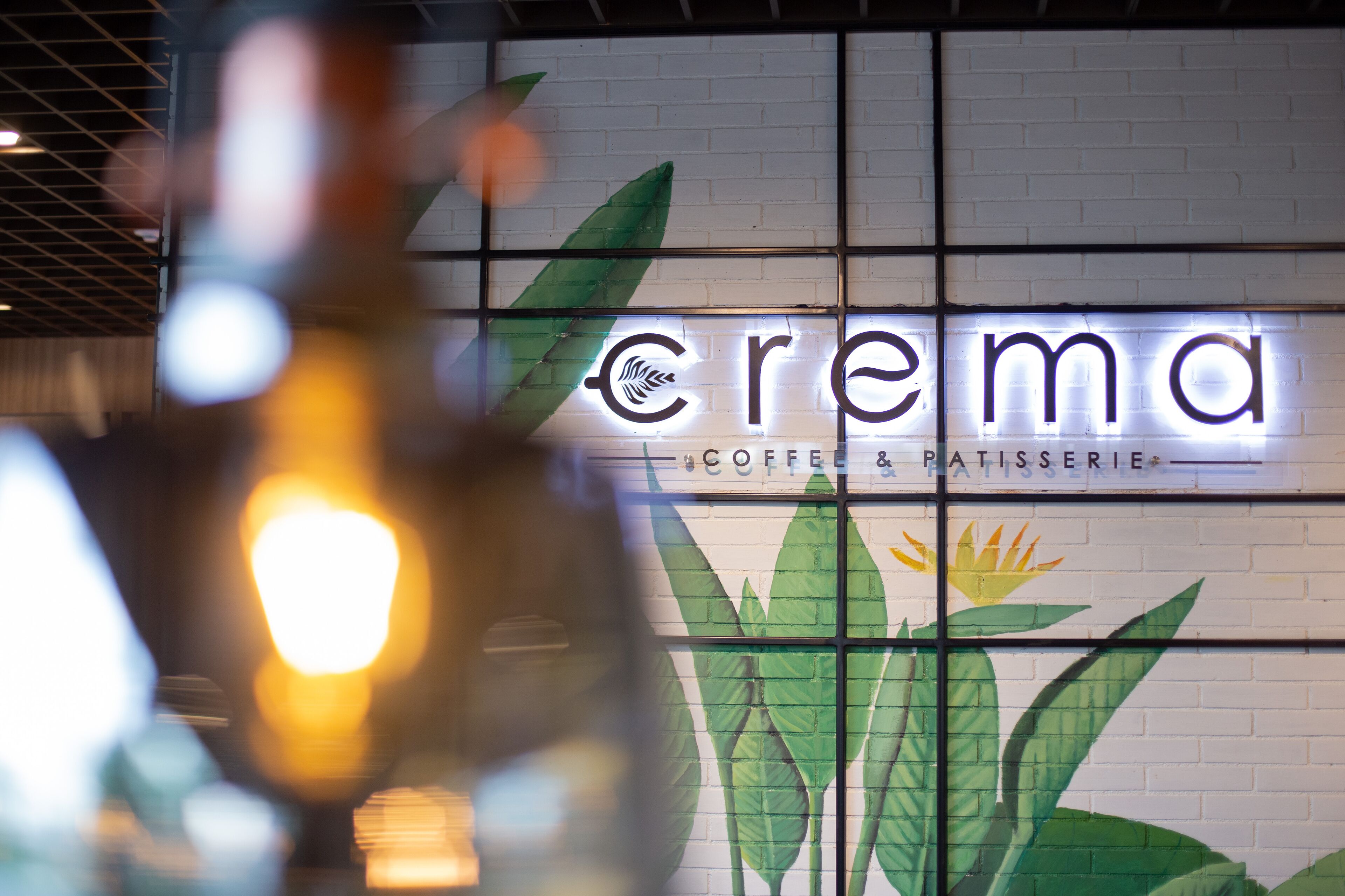 A cafe named "Crema" with a sign that includes a coffee and pastry menu.