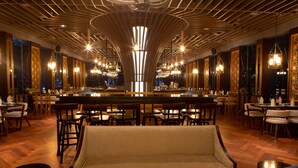 Een bar met een centrale piano, diverse zithoeken en een modern plafondontwerp.