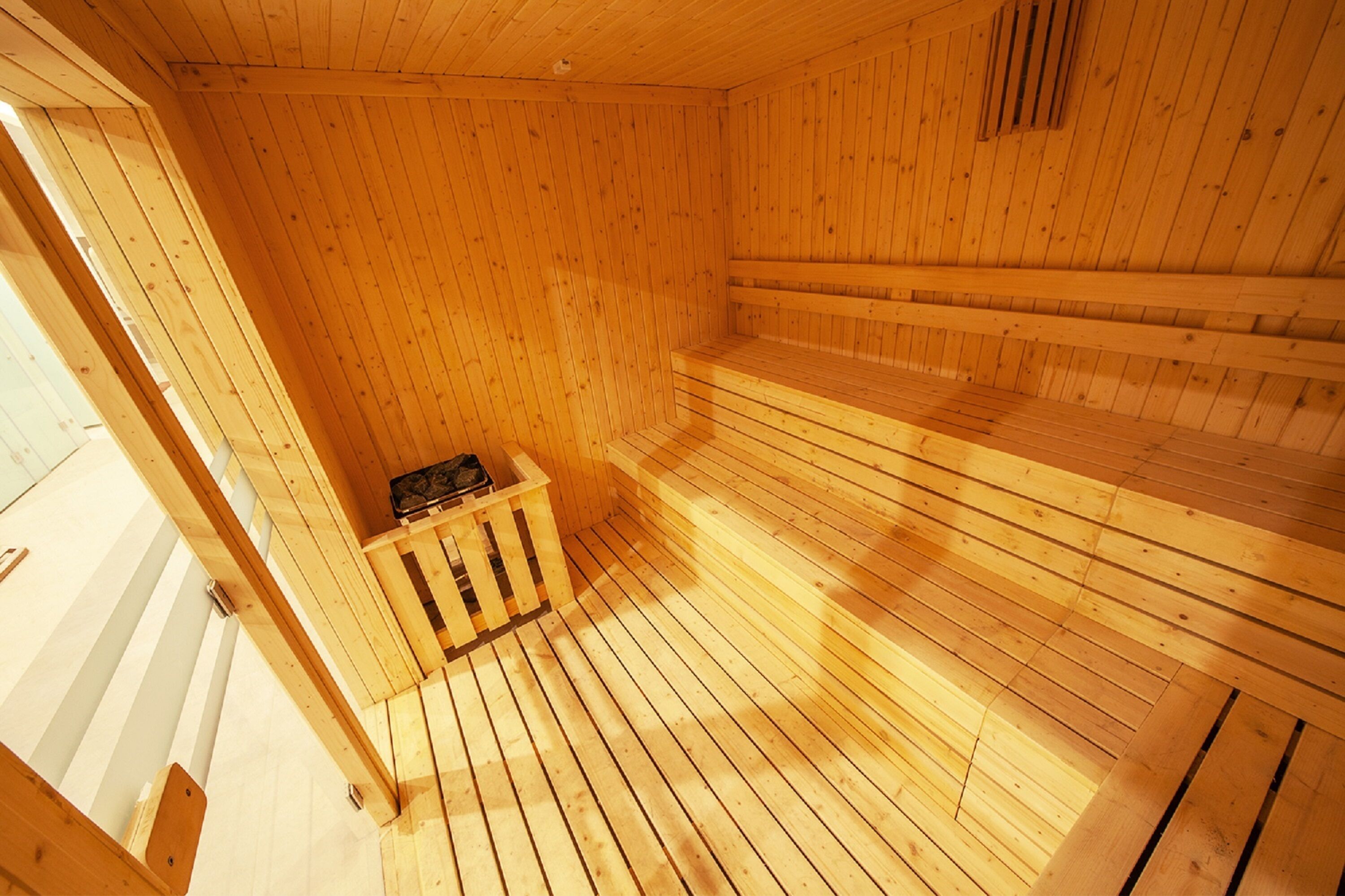 Een sauna met houten wanden en vloer, een bank en een kleine kachel.