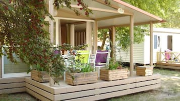 Un espacio al aire libre con techo, bancos de madera y jardineras, una entrada cubierta y un letrero que indica un área de jardín.